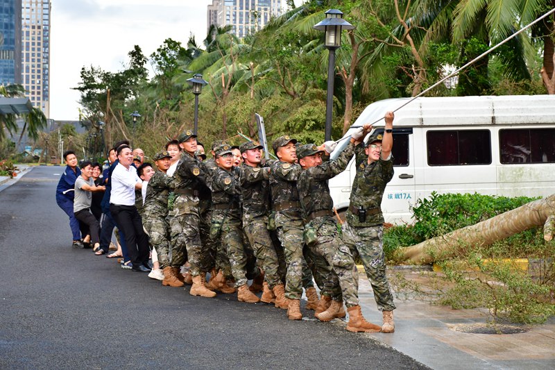 在災(zāi)后重建工作中，武警?？谥ш?duì)官兵和群眾一起移除砸壞車輛的樹木。袁琳松攝